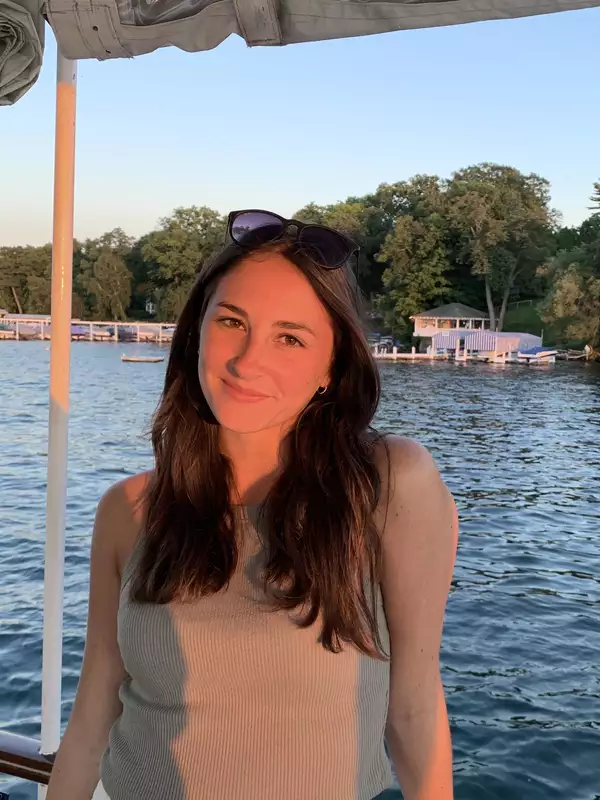 woman standing in front of water smiling with the sun on her face