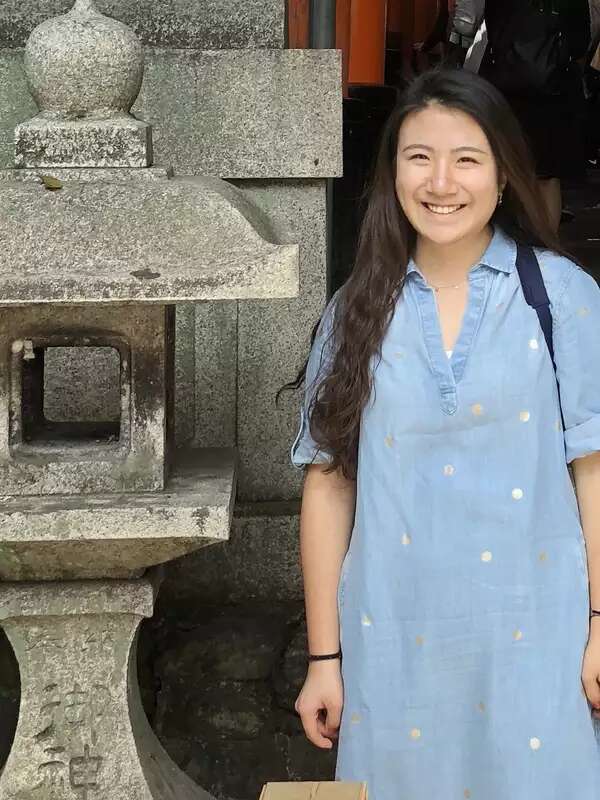 picture of Grace standing next to a statue and smiling in a blue dress