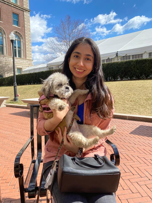 An image of Aarushi smiling while holding a small dog on a sunny day on Columbia's campus.