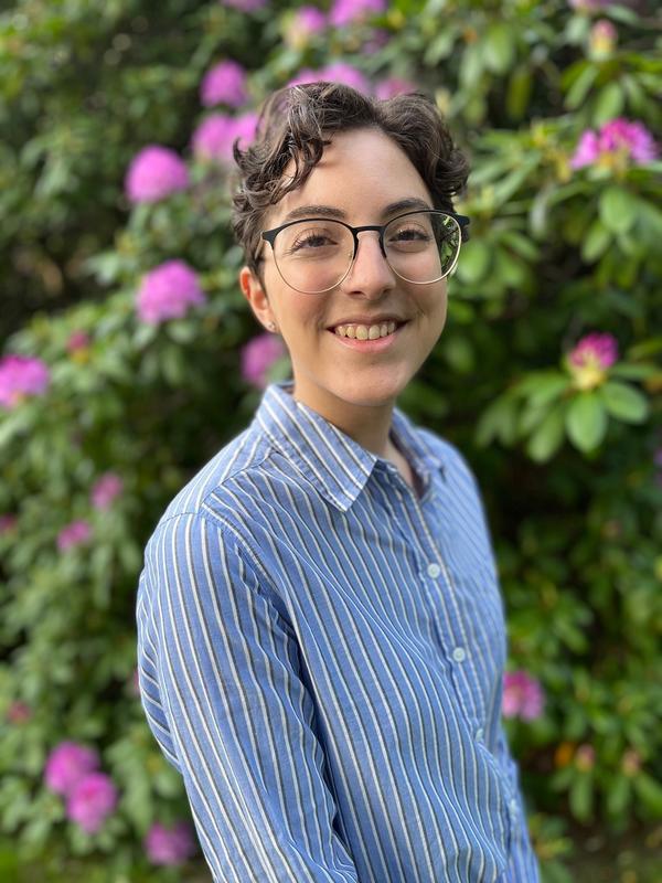 Madeline Liberman wearing a blue collared shirt in front of flowers
