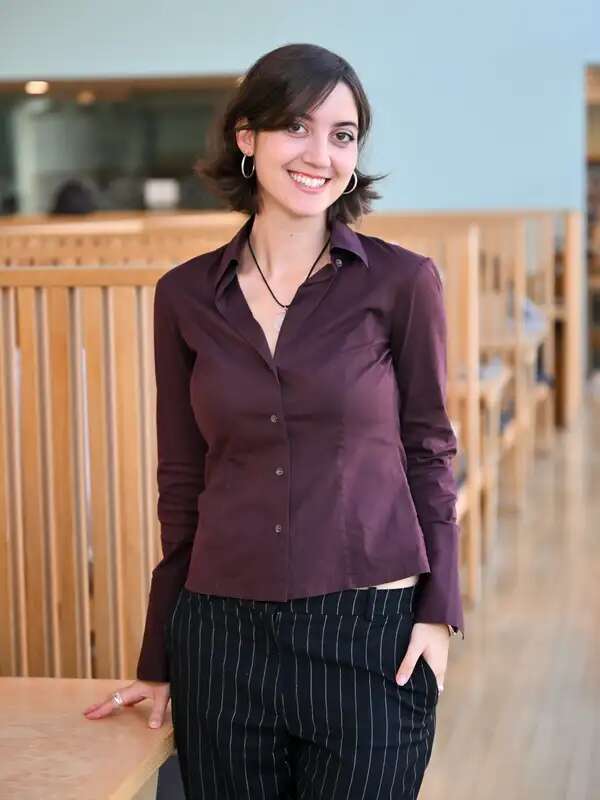Girl standing next to a desk wearing purple shirt